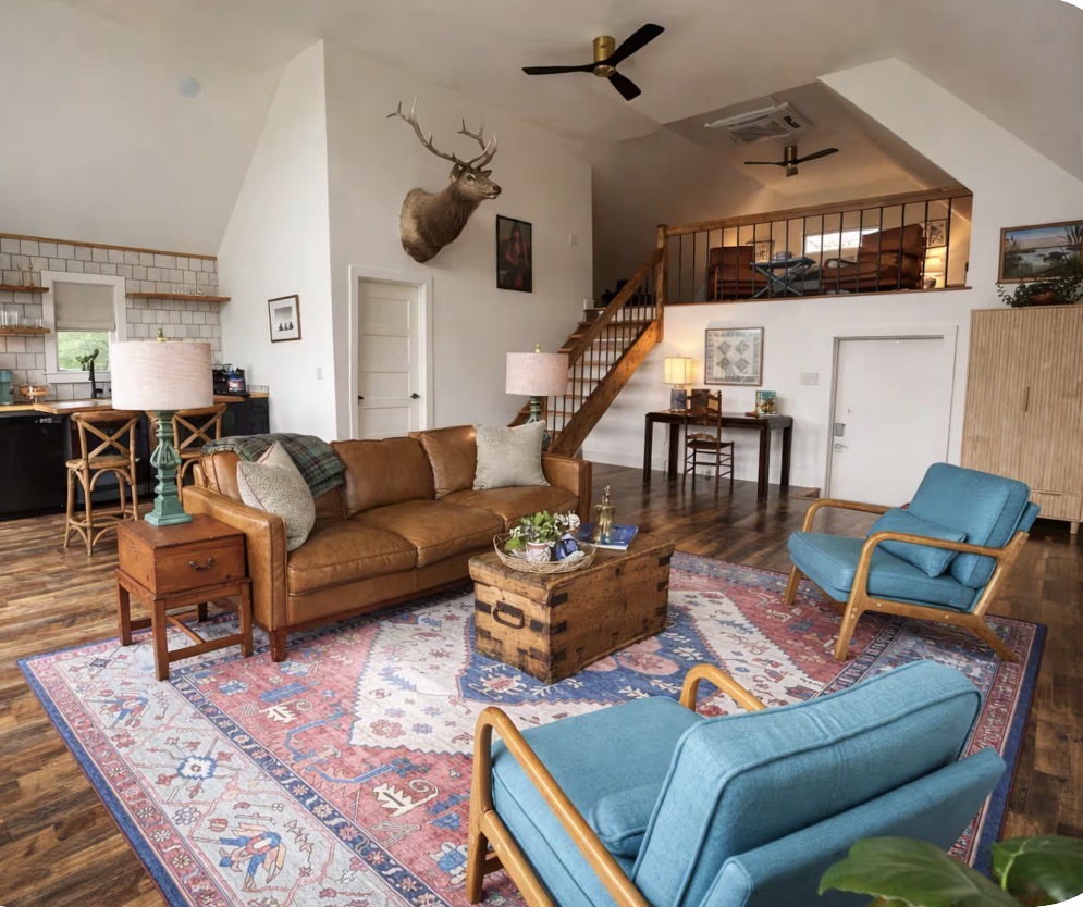 The Rockhill cabin living room with a leather sofa, blue chairs, and sleeping loft