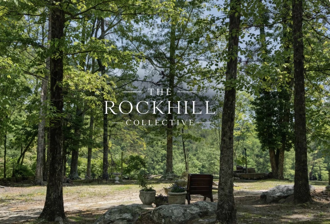 The Rockhill Collective name over a peaceful woodland garden with stone and antique seating